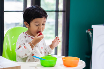 Photo of adorable young happy child toddler boy eating strawberry smiling close up looking at camera.