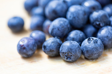 Several blueberries on a wooden surface with a blurred background