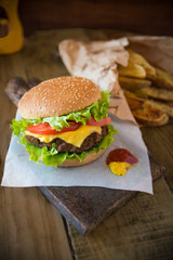 patatoes meat cheddar domatoes and green salads inside of delicious burger