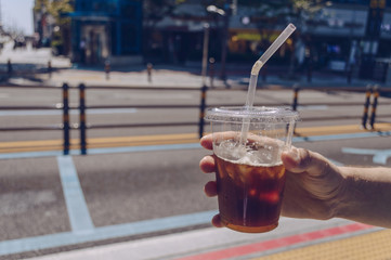 mans hand holding iced coffee cup