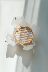 Сamembert cheese with white mold in paper packaging on a white background