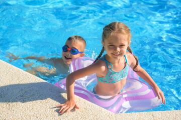 Children can swim in the outdoor pool. A young boy with goggles and a girl with an inflatable circle. Kids vacation.