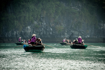 Halong bay, boats with passengers and boatmen rowing