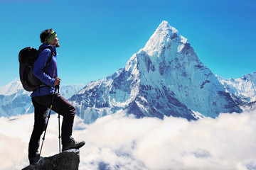 Young man hiker with backpack reaches the summit of mountain peak in Nepal, Everest region.