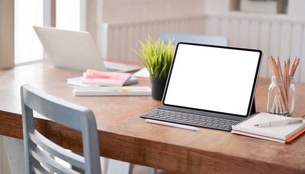 Mock up modern tablet and office equipment on the desk in a comfortable office.