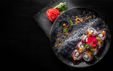 sushi roll with tuna, cream cheese, cucumber, rice in plate on black wooden table background