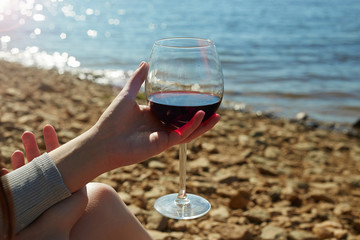 Female hand with Wine. girl on the beach holding a glass of red wine
