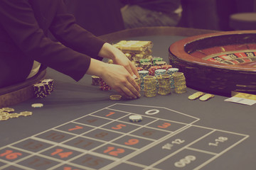 Hands of the croupier with chips on the gaming table in the casino