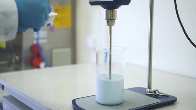 chemist hand add pour powder to liquid reagent in chemical mixing stirrer in laboratory Spbd. scientist in pharmaceutical lab finding cure vaccine test for coronavirus covid19. concept magnetic