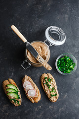 Fresh homemade chicken liver pate with herbs. Bread bruschetta with liver pate with onion, cucumber and radish. Top view, side view on a dark background. space for text.