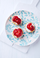 Little mascarpone tart with fresh 
strawberries on wooden background. Top view.	