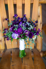 Fototapeta na wymiar all purple wedding bouquet sitting on wooden chair