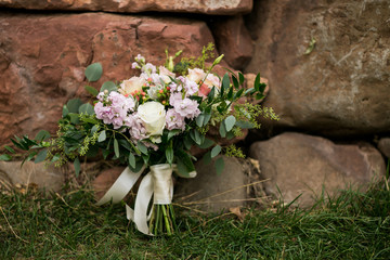 wedding bouquet with roses leaning against red rocks outside