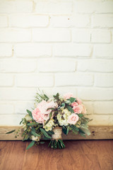 pink rose bouquet leaning against vintage brick wall for wedding with copy space