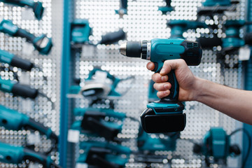 Male worker hand holds electric drill, tool store