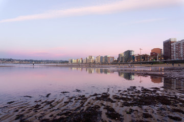 reflections of the city in the sea, at sunset with pink colors