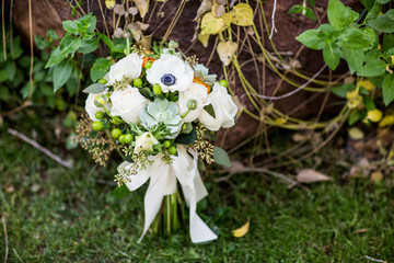 Obraz na płótnie Canvas white wedding bouquet leaning on wall with vines and green grass
