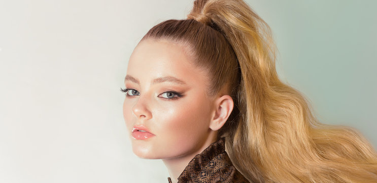 Closeup portrait of a woman with a long tail made of hair. Female face in profile. White and blue gradient background.