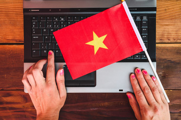 woman hands and  flag of Vietnam on computer, laptop keyboard
