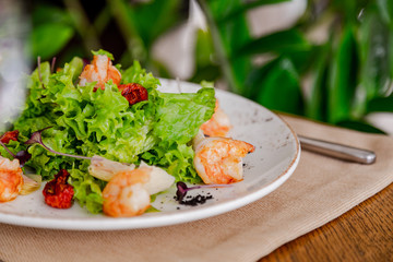 light healthy salad of fresh vegetables and shrimp. Photo in the interior