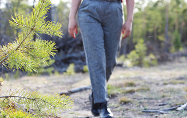 
young girl in trousers walks through the forest