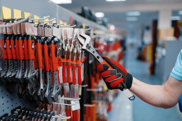 Worker choosing adjustable wrench in tool store