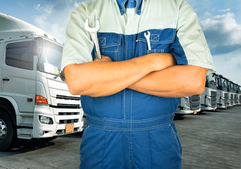 Professional auto technician holding wrench with semi truck on parking, maintenance and repairing 