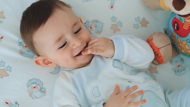 Close up of nice caucasian newborn baby on the bed and sucking a pacifier