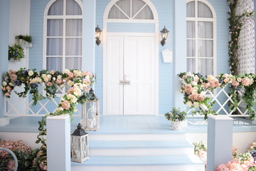 Porch of the house with white door , windows and stairs, handrails with beautiful flowers , sweet family home concept