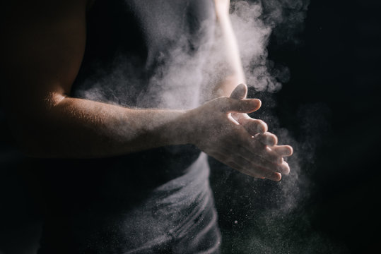 Close-up Of Unrecognizable Muscular Man Clapping Hands With Talc And Preparing For Workout At Gym. Closeup Of Athletic Male Hands Preparing For Fit Workout In Gym With Chalk Magnesium Carbonate.