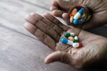 Elderly woman pouring pills from bottle on hand with copy space 
