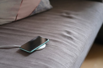 one smartphone on wireless charger on sofa. blur background