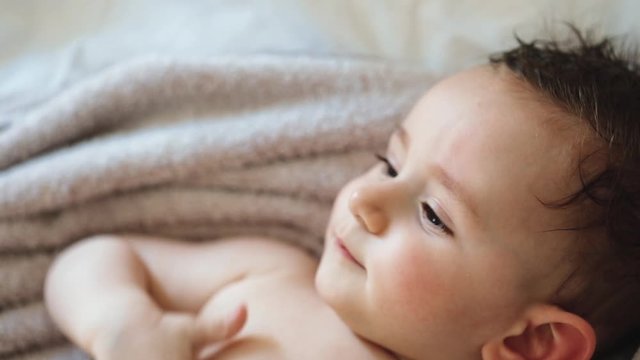 Close up of nice caucasian newborn baby on the bed and sucking a pacifier