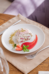 beautiful tasty green vegan dessert pistachio strawberry rolls on a wooden table in the interior.