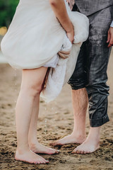 Fototapeta na wymiar Loving couple, bride and groom on the beach, male and female legs in drops of water
