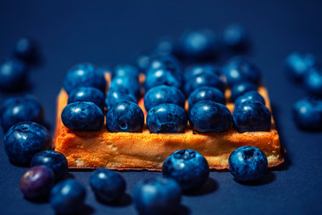 Sweet Homemade waffles with fresh raspberries, blueberries and cream on wooden table background