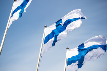 Three finnish national flags on the wind against the blue sky