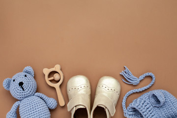 Flat lay composition with baby accessories set: crib shoes, teddy bear toy, knitted hat, wooden...