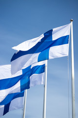Three finnish national flags on the wind against the blue sky