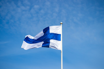 Fototapeta premium Finnish national flag on the wind against the blue sky