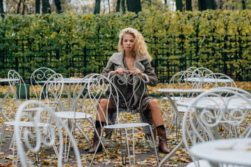 Young blond girl sitting at table in public park - 349900317