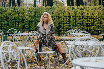 Young blond girl sitting at table in public park - 349900363