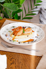 mashed potatoes with cutlet, on a beautiful white plate. The dish is decorated with micro-greens. Against the background of a wooden table in the interior.