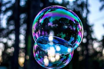 two sticky soap bubbles fly in the air. they see reflections and the play of light