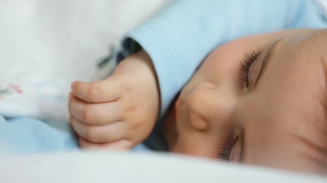 Close up of nice caucasian newborn baby on the bed and sucking a pacifier