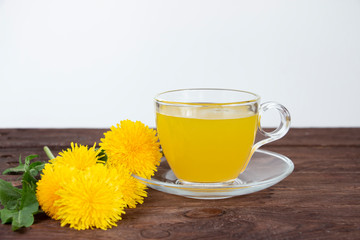 Glass cup with dandelion tea on a dark wooden table. Phytotherapy. Alternative medicine concept.