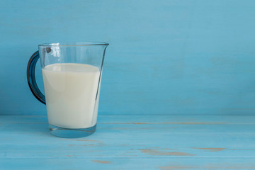 Jug of milk on blue wooden background with copy space.