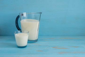 milk in a glass jug and in a glass on blue wooden background with copy space. World Milk Day.