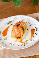 mashed potatoes with cutlet, on a beautiful white plate. The dish is decorated with micro-greens. Against the background of a wooden table in the interior.