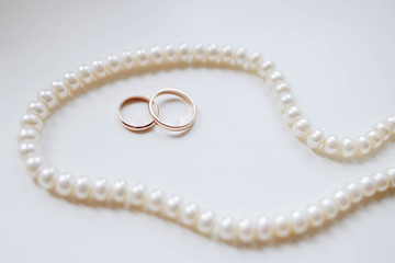 Wedding gold rings on a white background surrounded by pearls